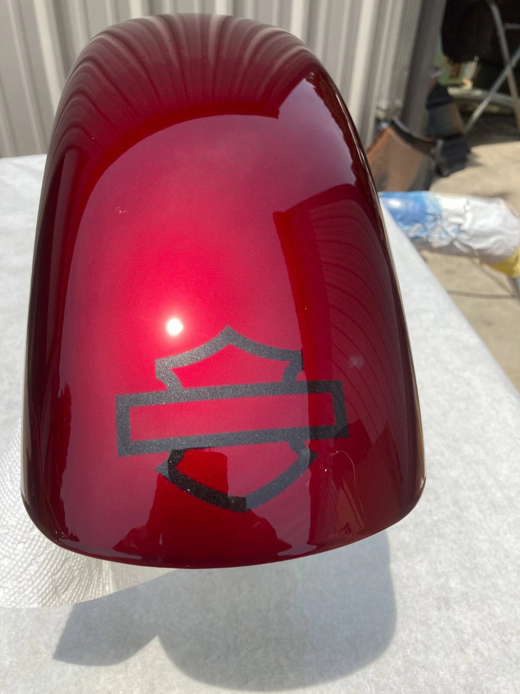 Candy red Harley motorcycle fender with a logo painted with HS 99 on a white surface